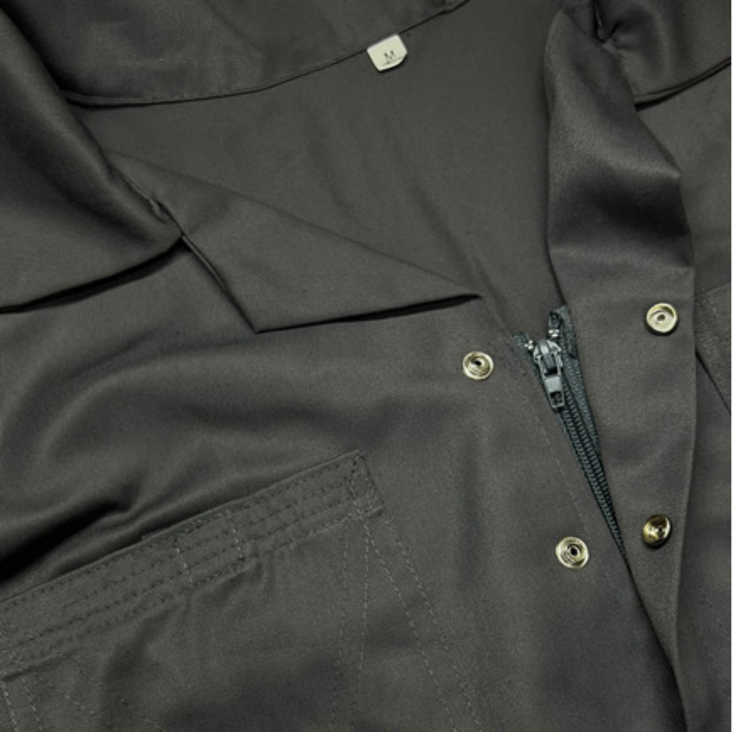 Close-up of a gray coverall with zippers and buttons
